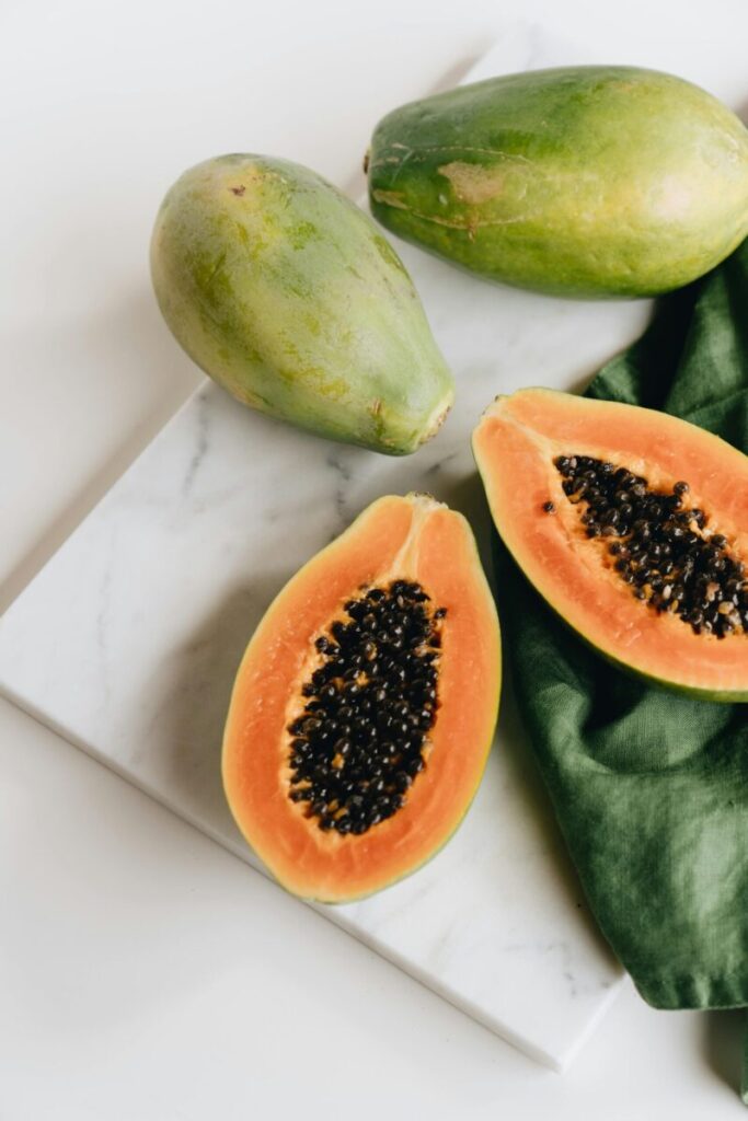 Ripe papaya halves with seeds on a marble board, perfect for healthy snacking.